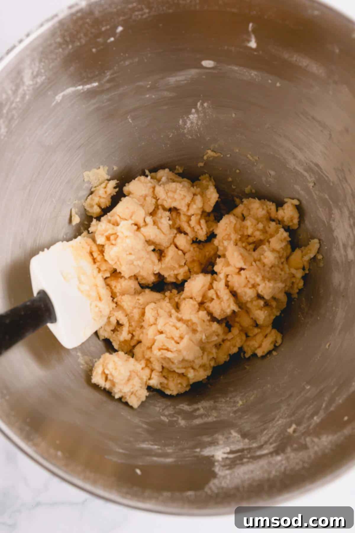 Light and fluffy snowball cookie dough in a mixing bowl after creaming butter, sugar, and vanilla.