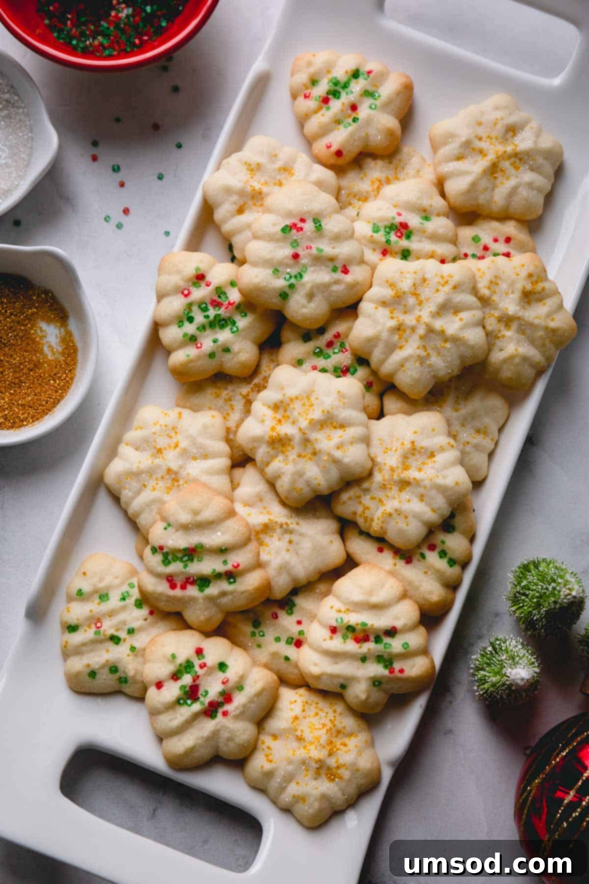 A beautifully arranged plate of holiday-shaped almond spritz cookies, ready to be enjoyed.