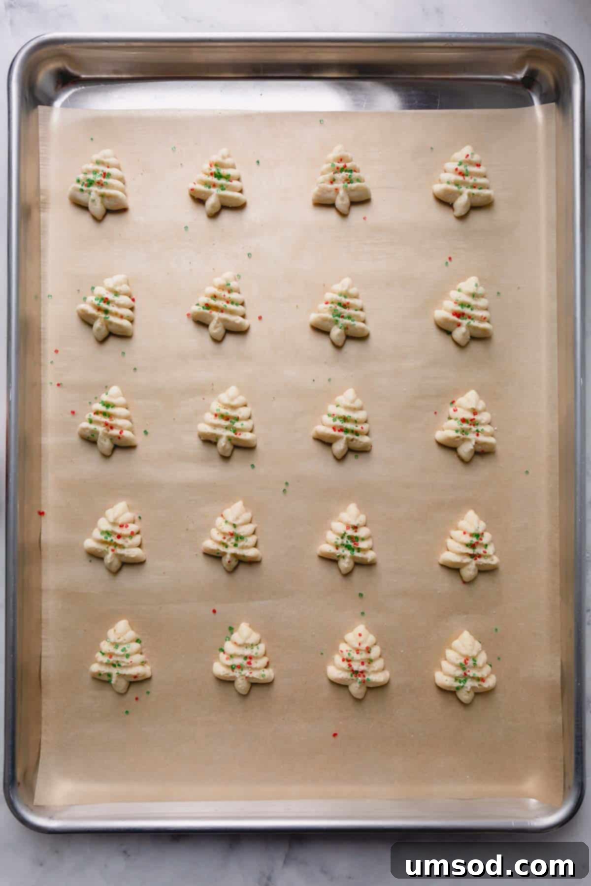 A baking sheet filled with unbaked spritz cookies, neatly arranged and ready for the oven.