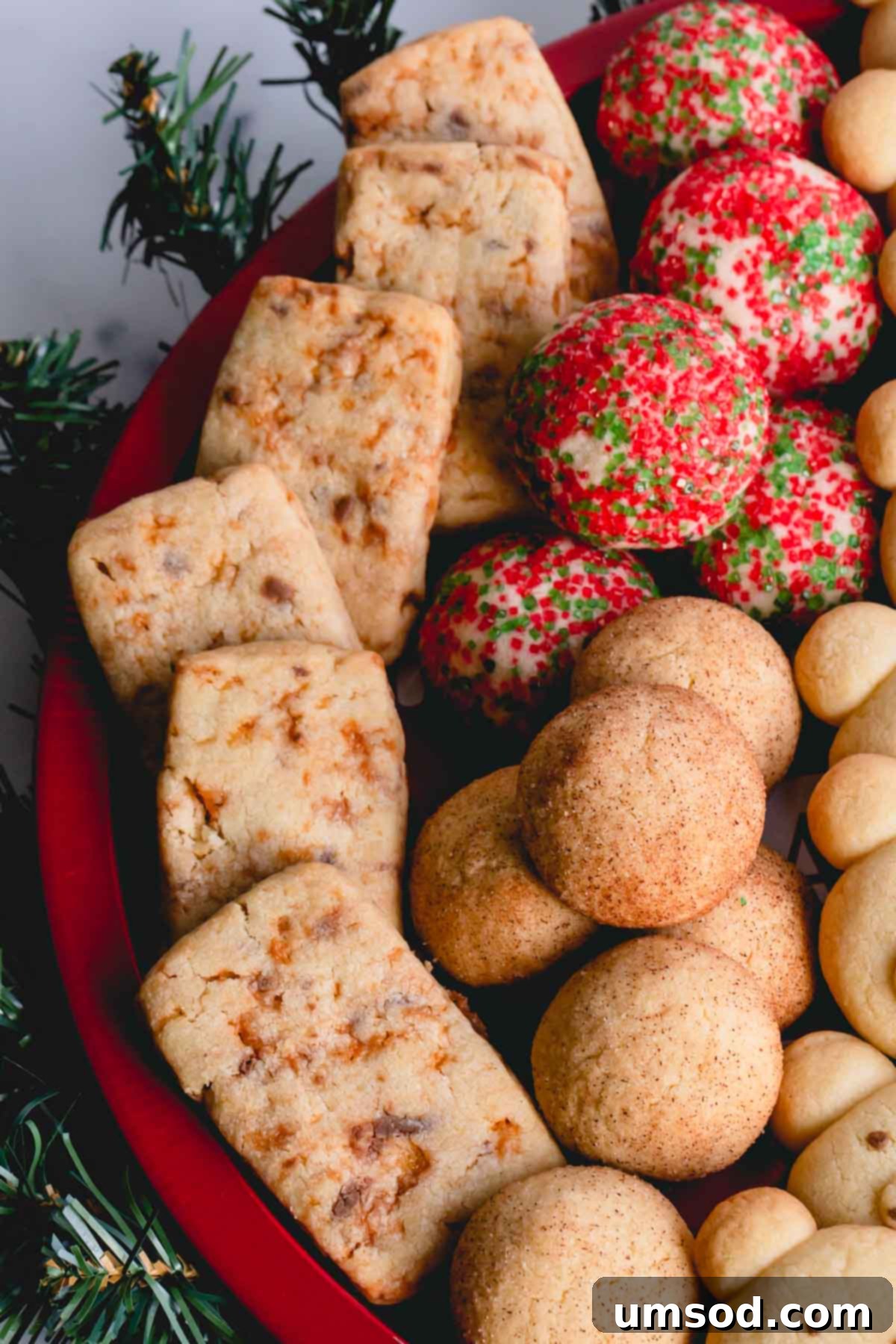 Tek Hamurdan 6dan Fazla Lezzet: Efsanevi Tereyağlı Kurabiye Hamuru 16 A vibrant red platter adorned with freshly baked Butterfinger butter cookies, showcasing their golden-brown edges and candy-filled centers.