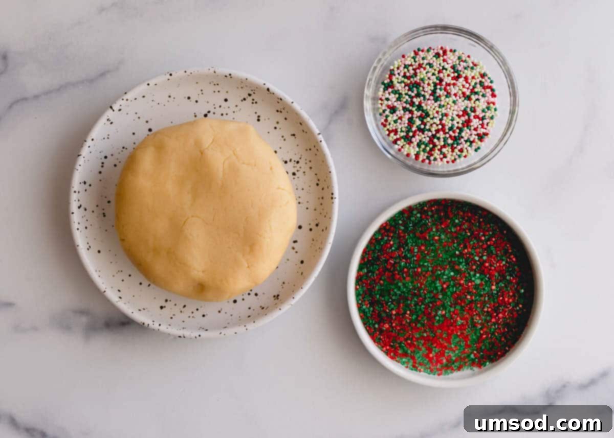 Tek Hamurdan 6dan Fazla Lezzet: Efsanevi Tereyağlı Kurabiye Hamuru 17 A cookie dough ball alongside two bowls filled with various holiday sprinkles and colored sugars, ready for decorating festive cookies.