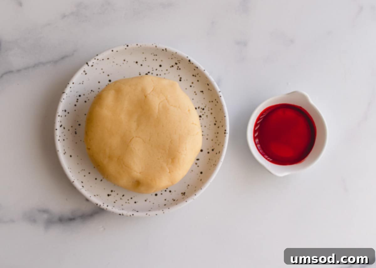 Tek Hamurdan 6dan Fazla Lezzet: Efsanevi Tereyağlı Kurabiye Hamuru 8 A single ball of cookie dough alongside a small bottle of red food coloring, ready for making candy cane cookies.