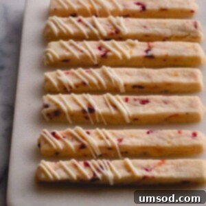 orange cranberry shortbread cookie sticks on cutting board.