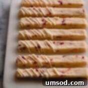 orange cranberry shortbread cookie sticks on cutting board.