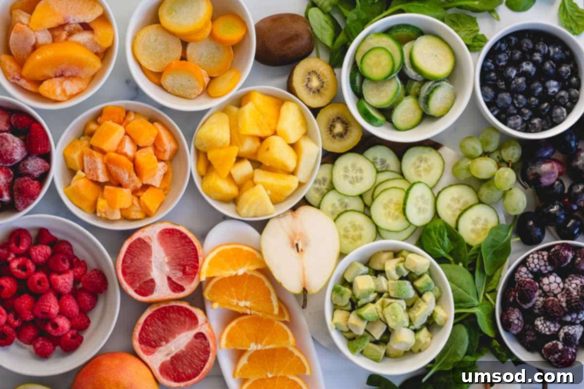 Assortment of fresh fruits and vegetables like oranges, pineapple, cucumbers, spinach, and kiwi, ready for blending.