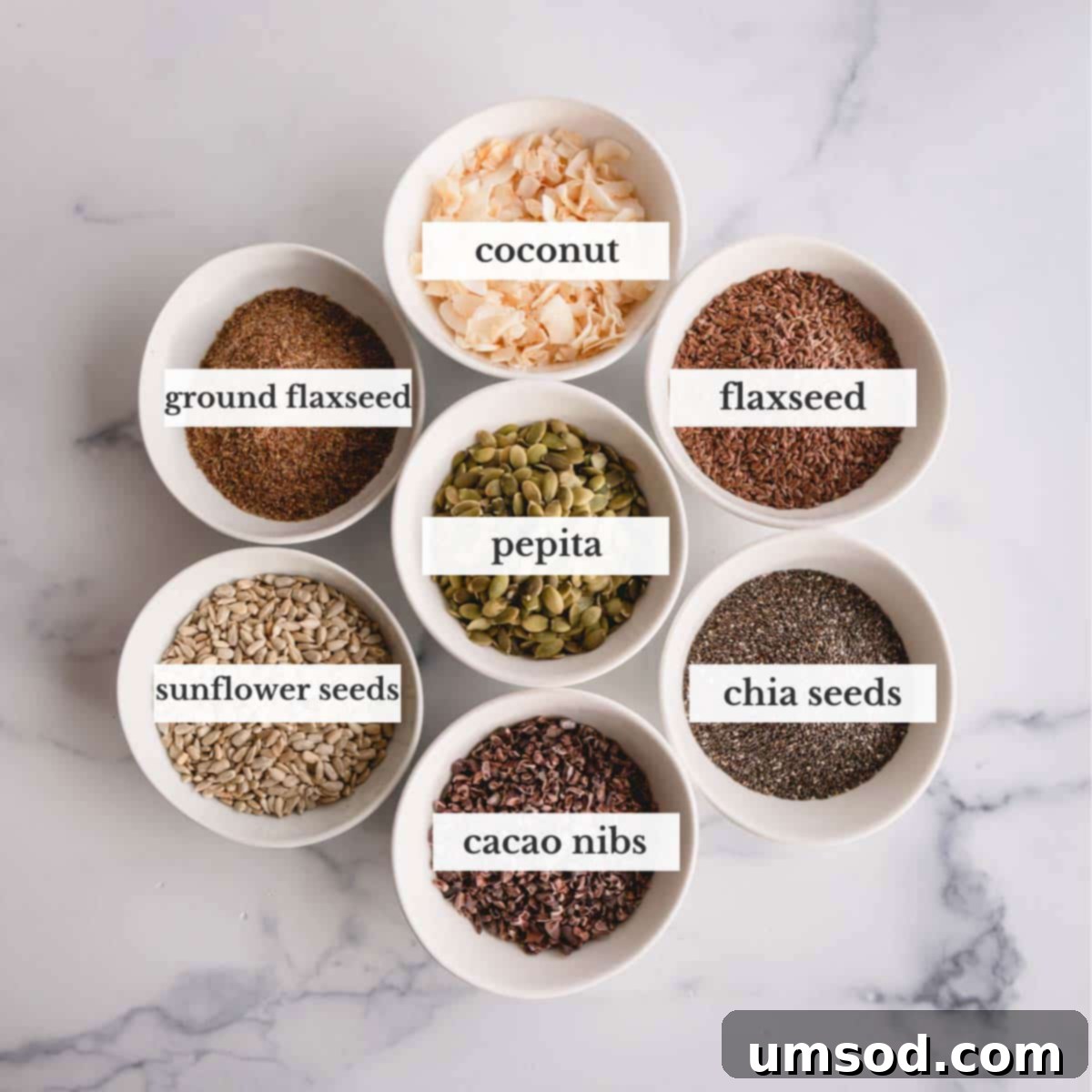 Various smoothie toppings including toasted coconut, flaxseed, pepitas, sunflower seeds, chia seeds, and cacao nibs.