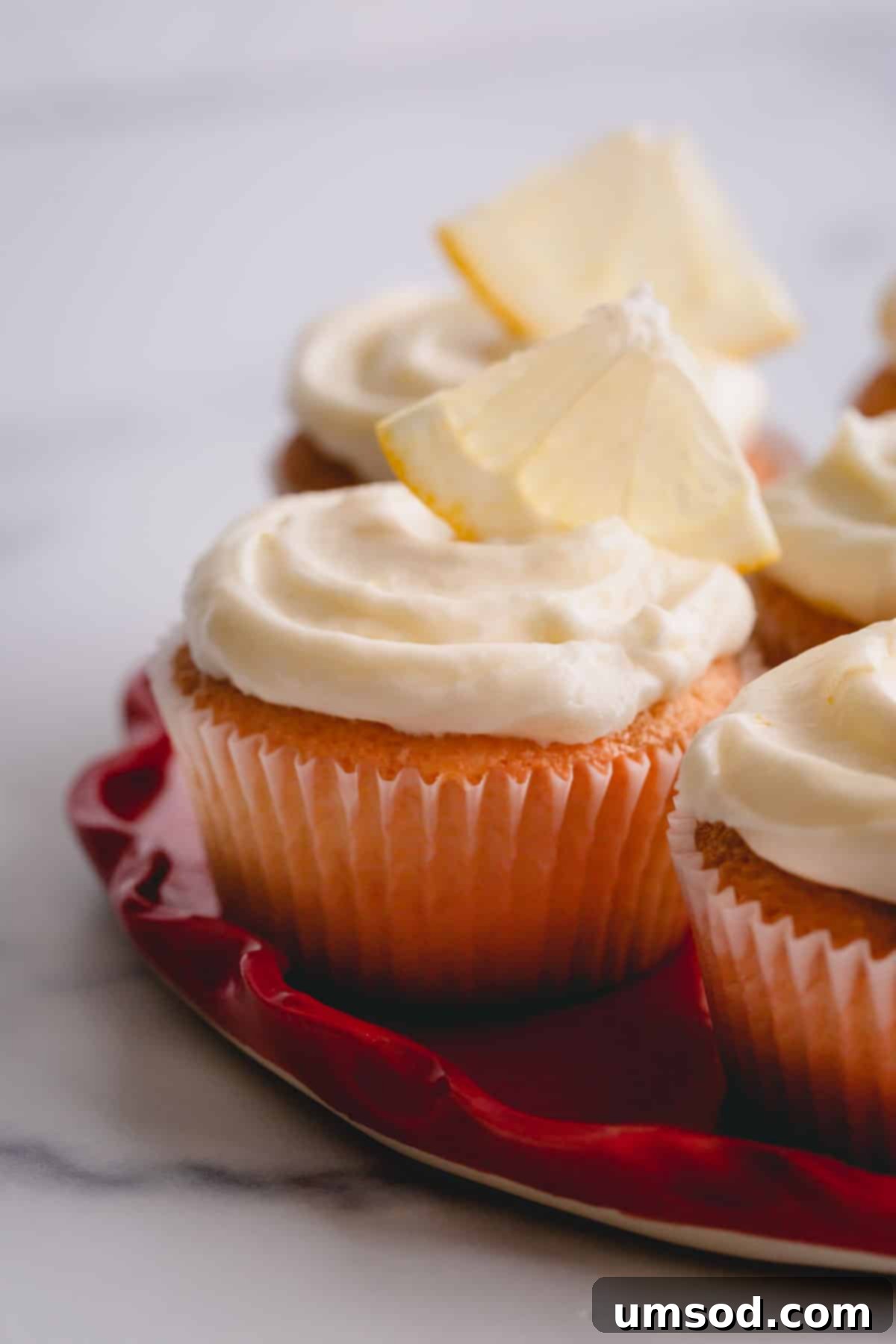 lemon cupcakes with cream cheese frosting on a platter.