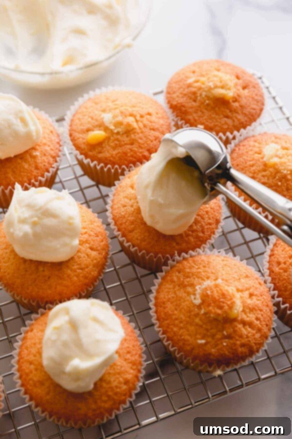 scooping frosting onto lemon cupcakes.