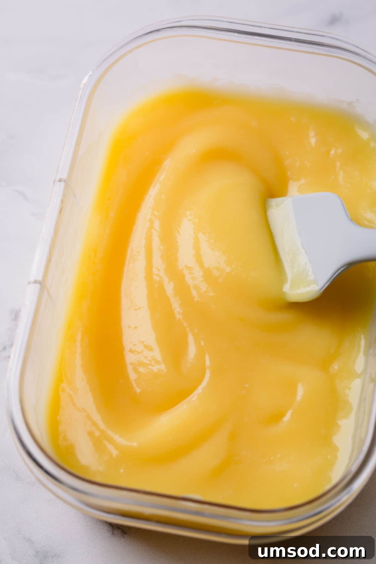 Creamy lemon curd in a clear storage container.