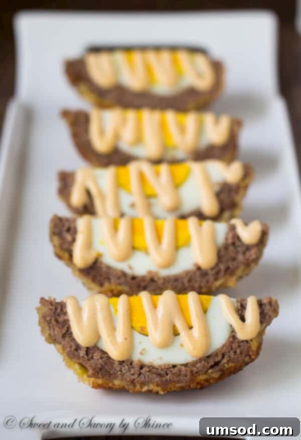 Three beautifully prepared Scotch eggs, presented on a rustic wooden board, sliced and ready to be served.