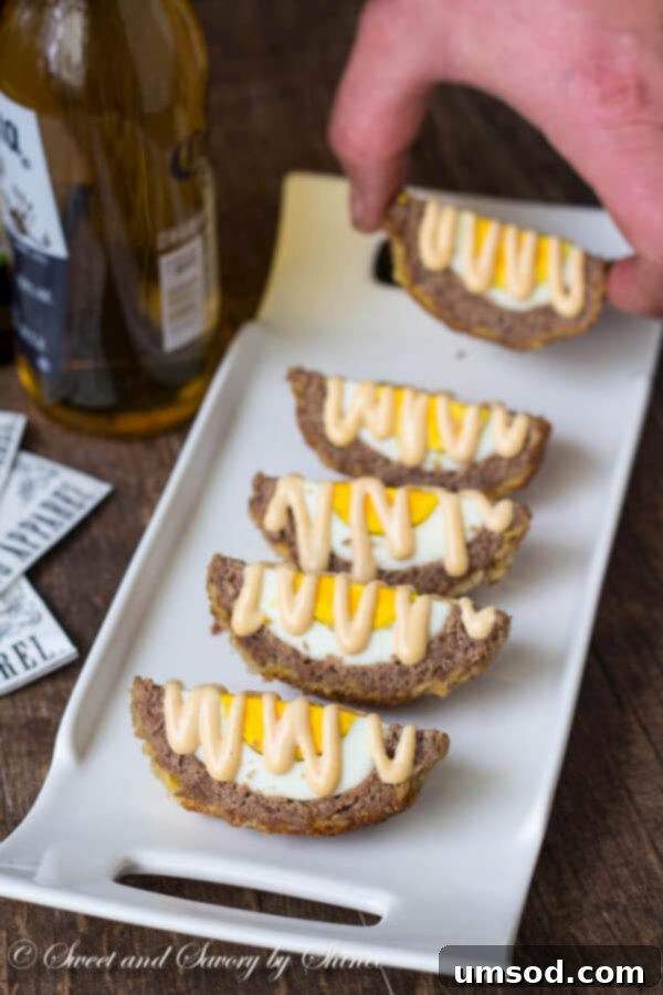 A platter of sliced Scotch eggs, generously drizzled with the special mustard sauce, beautifully arranged for a party or gathering.