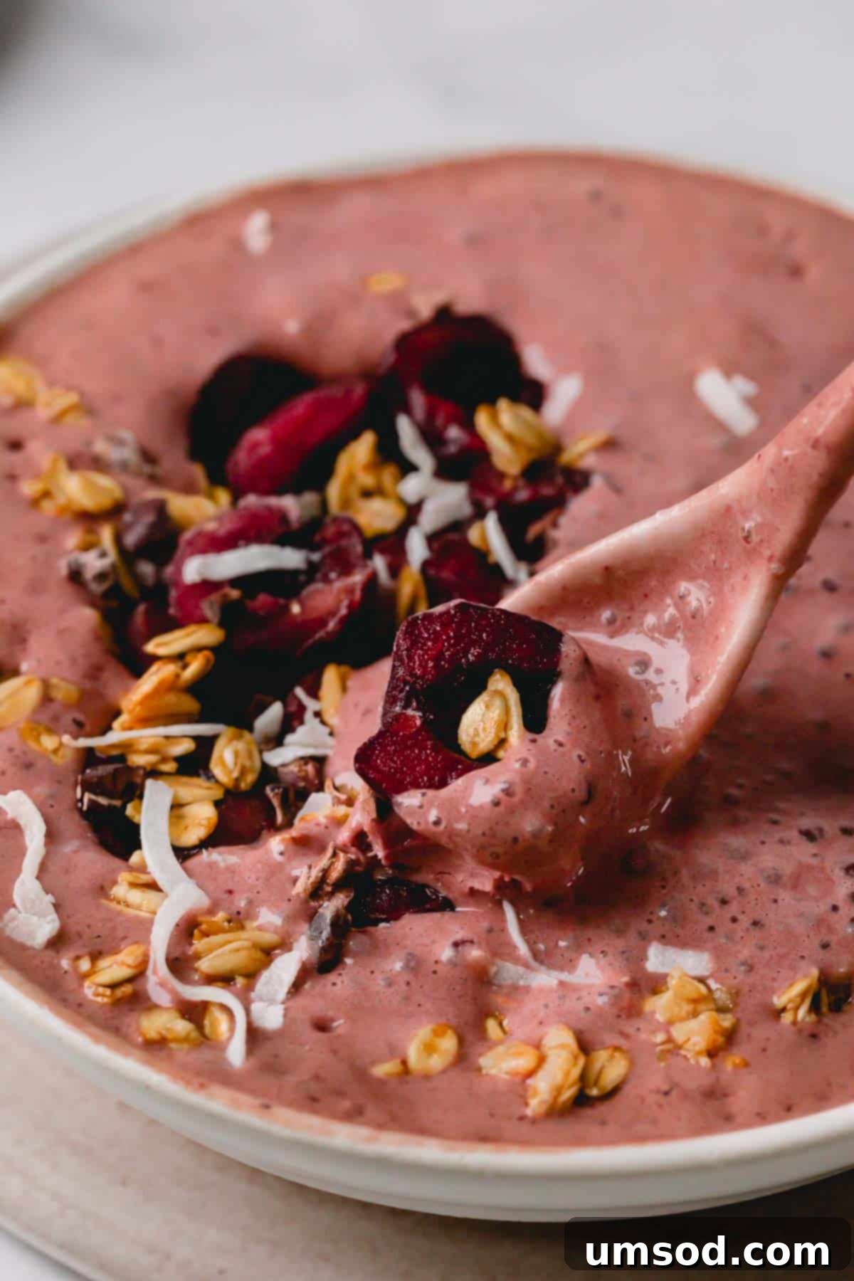 A vibrant, thick Black Forest Smoothie Bowl, generously garnished with fresh cherries and a spoon poised to scoop, highlighting its creamy texture.
