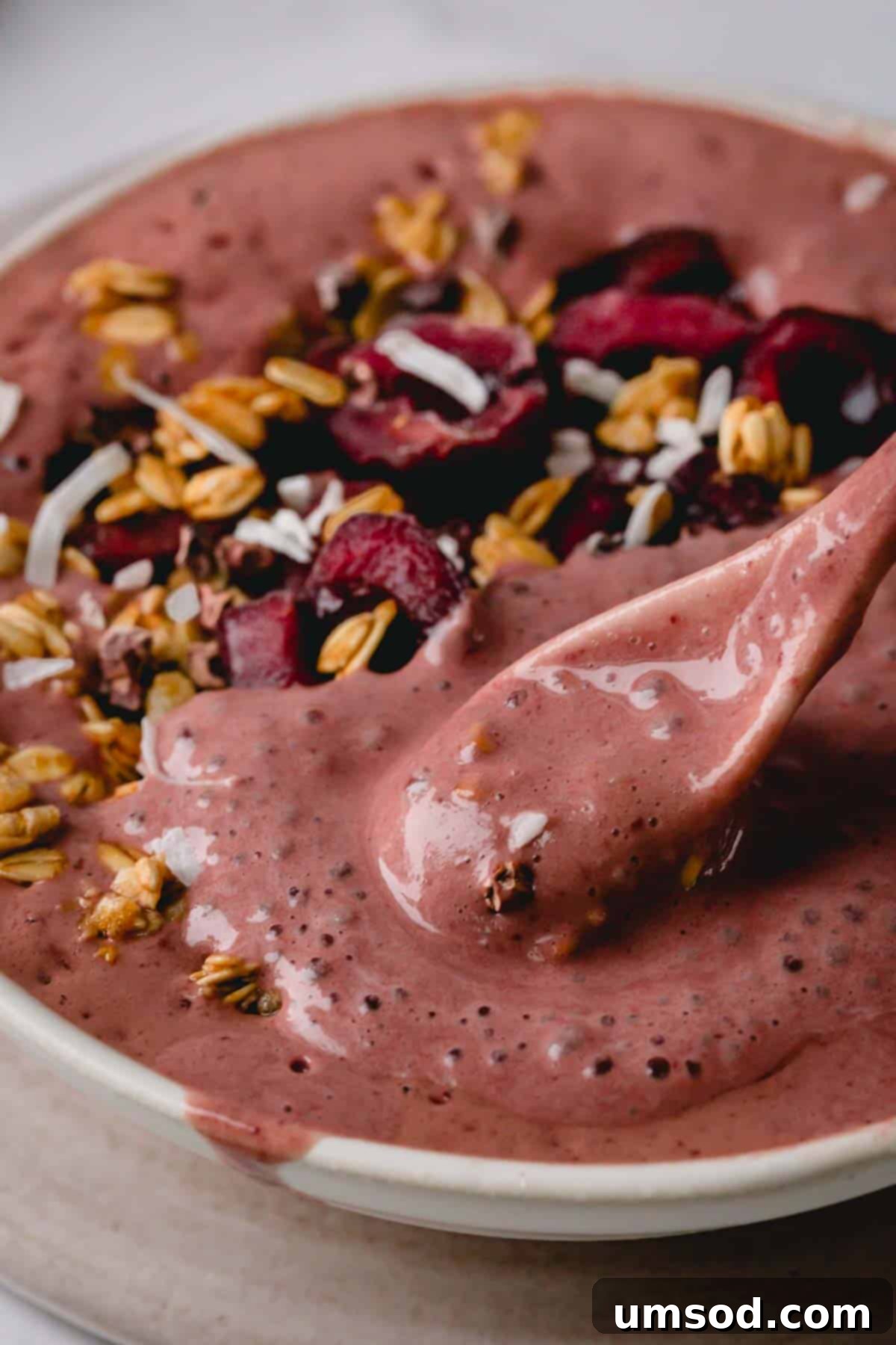 A close-up view of a spoonful of Black Forest Smoothie Bowl, clearly showing its thick, creamy texture and a medley of delectable toppings, emphasizing the deliciousness of each bite.