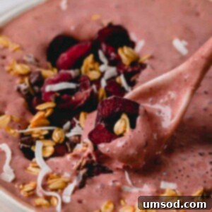 A spoonful of chocolate cherry smoothie bowl, garnished with fresh cherries, highlighting the recipe's delicious appeal.