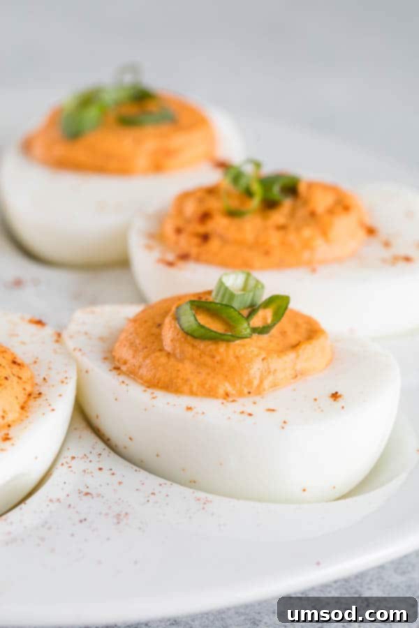 Delicious Roasted Red Pepper Deviled Eggs arranged on a platter, garnished with fresh herbs.