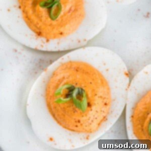 Close-up of a finished Roasted Red Pepper Deviled Egg, showcasing the vibrant filling and garnish.