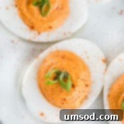 A close-up shot of the creamy filling being piped into egg whites for deviled eggs.