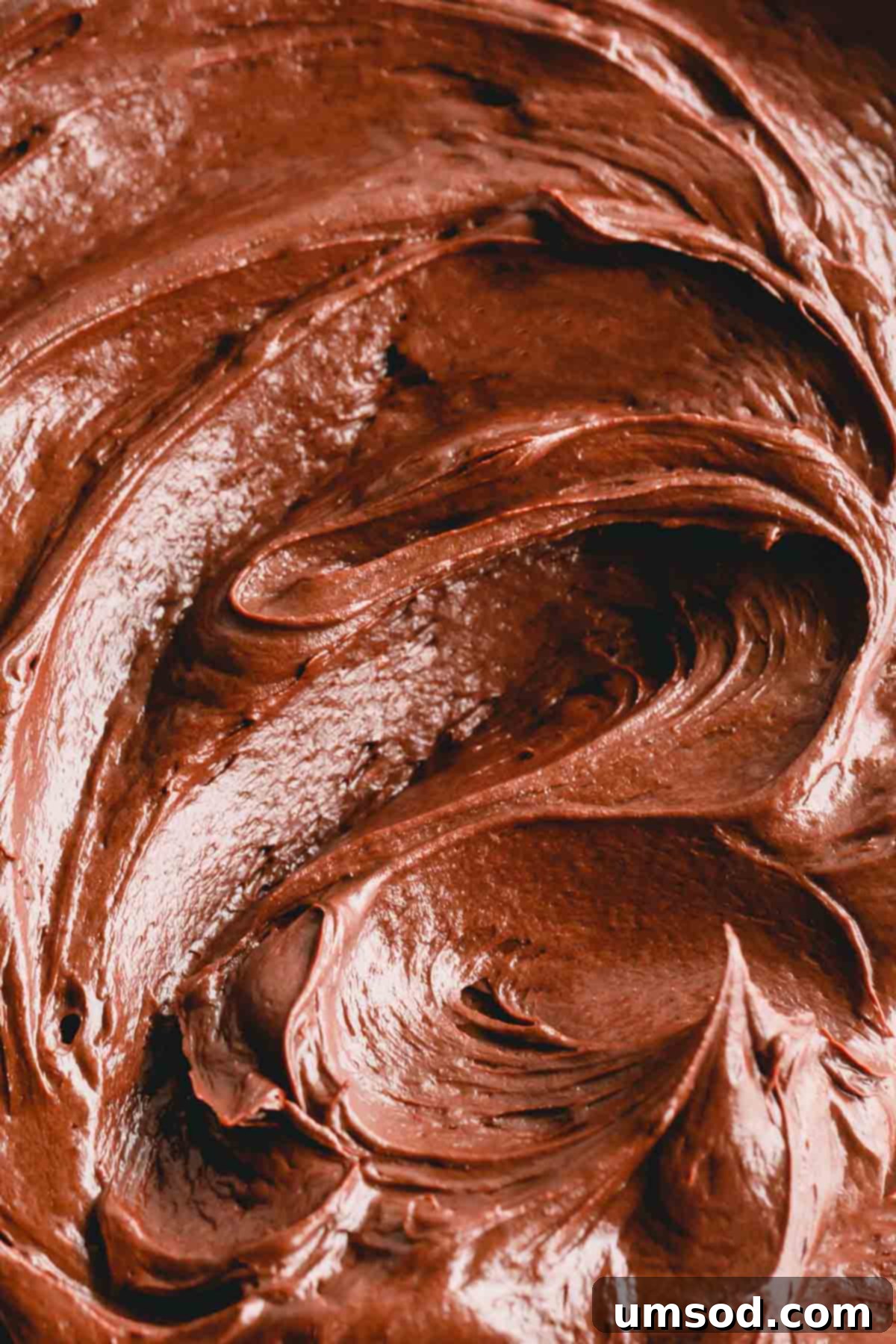 A close-up view of fluffy, smooth chocolate cream cheese frosting in a bowl, showcasing its luxurious texture.