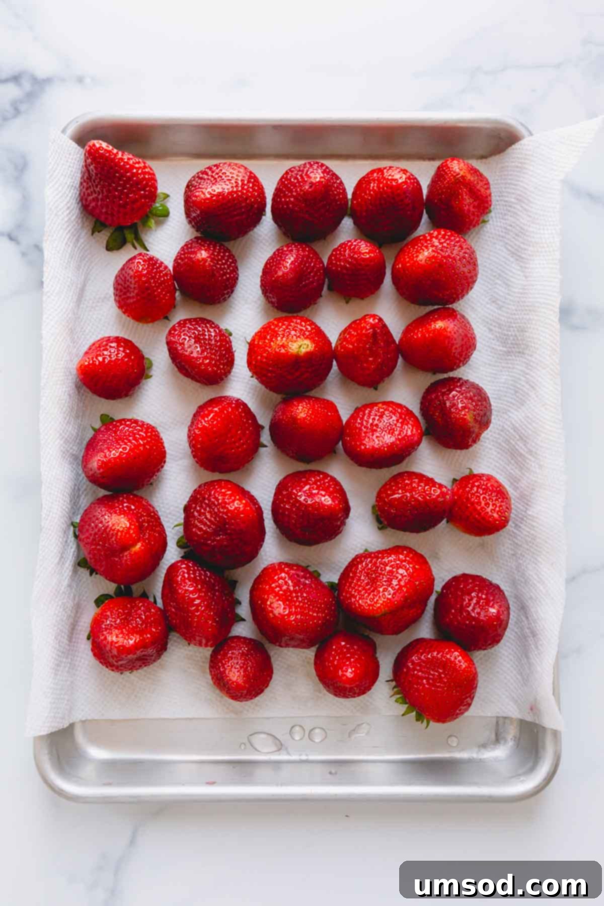 Clean strawberries on top of a paper towel-lined baking sheet.
