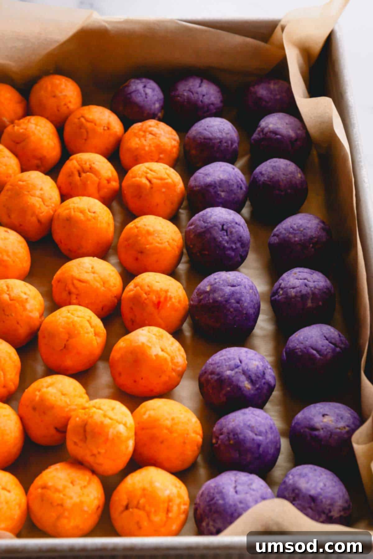 Ghoulishly Good Cake Pops 4 Orange and purple cake pop balls on top of parchment paper in a tray, ready for dipping.