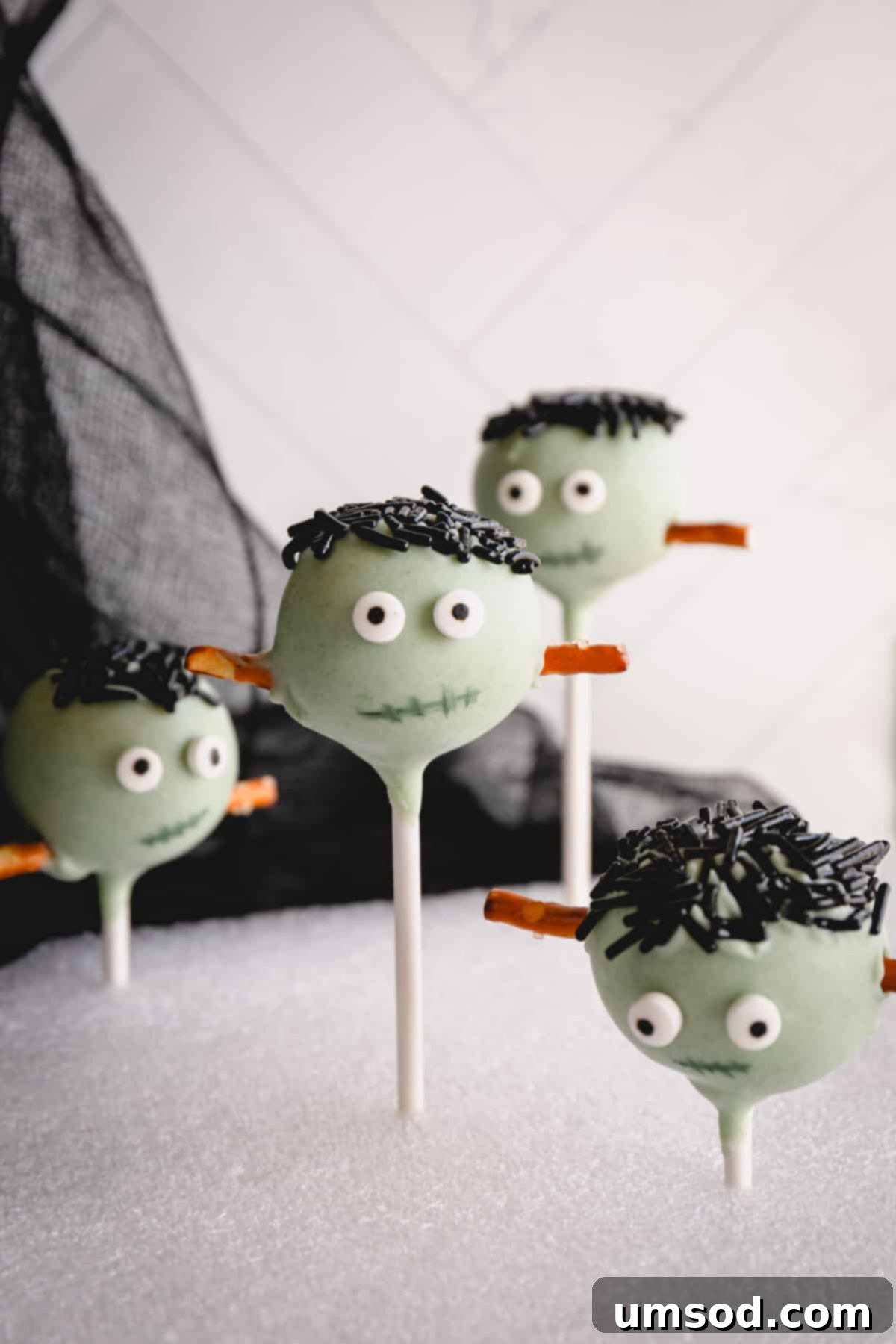 Ghoulishly Good Cake Pops 5 Frankenstein Halloween cake pops with green coating, black sprinkles for hair, and pretzel stick neck bolts.