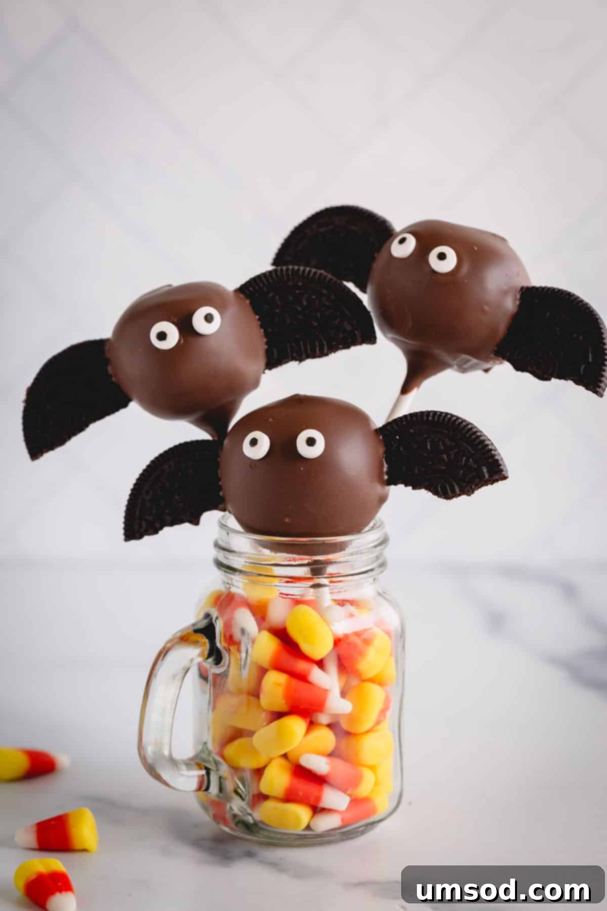 Ghoulishly Good Cake Pops 9 Bat cake pops elegantly arranged in a mason jar filled with colorful candy corn.