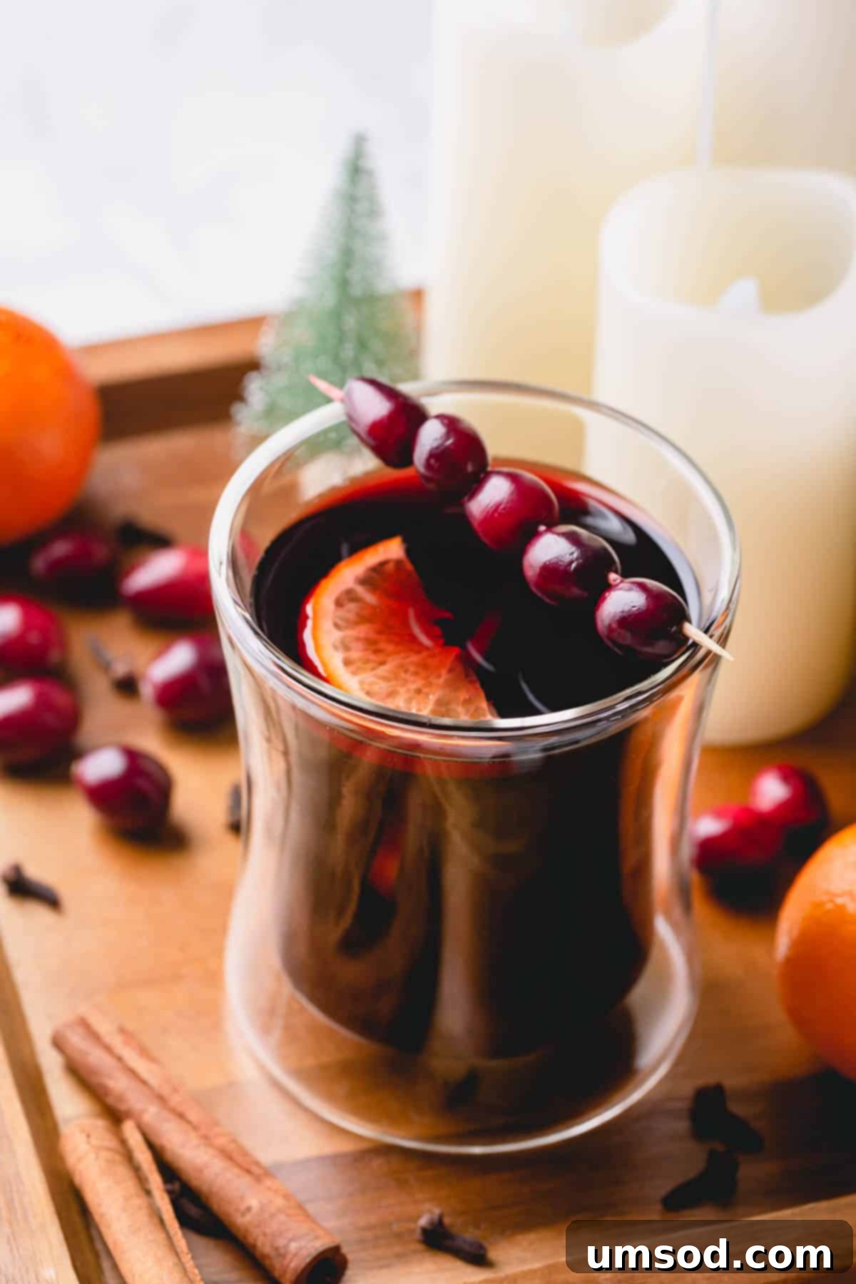 Mulled wine in a glass garnished with fresh cranberries and a slice of orange, evoking a cozy holiday atmosphere.
