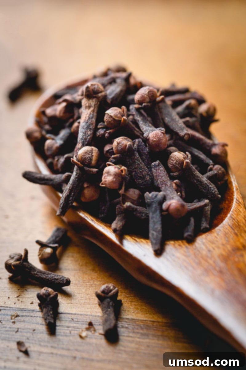 Close-up of whole cloves on a wooden spoon, highlighting their aromatic quality for mulled wine.