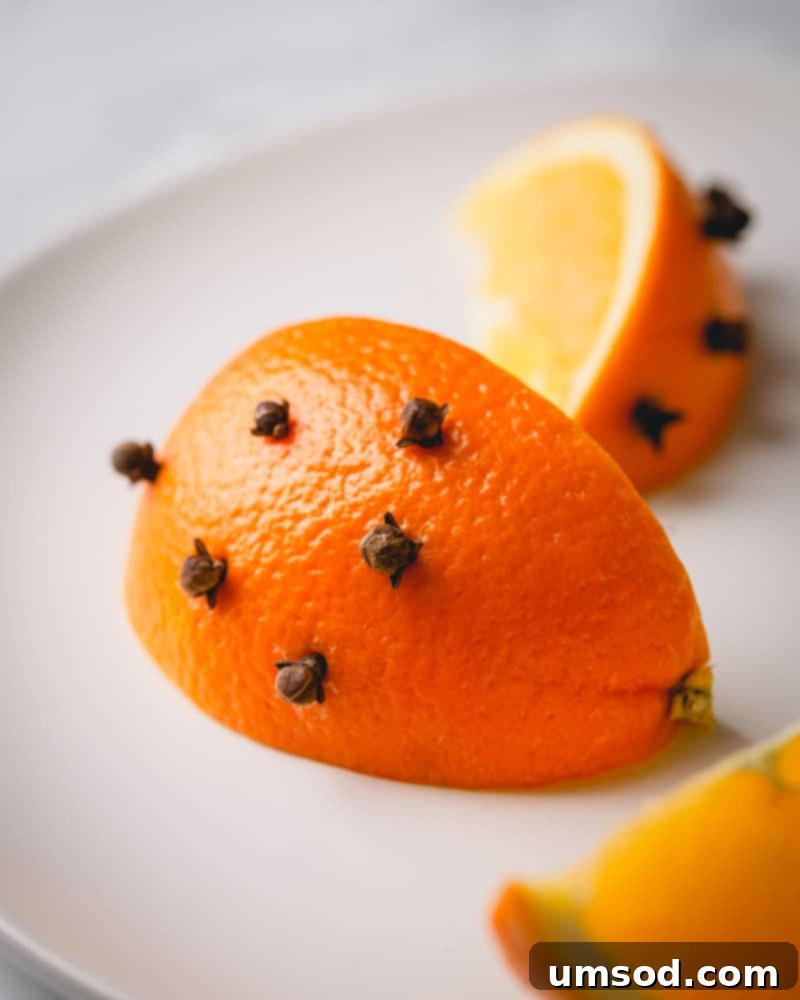 A wedge of orange, elegantly studded with whole cloves, ready for mulled wine preparation.