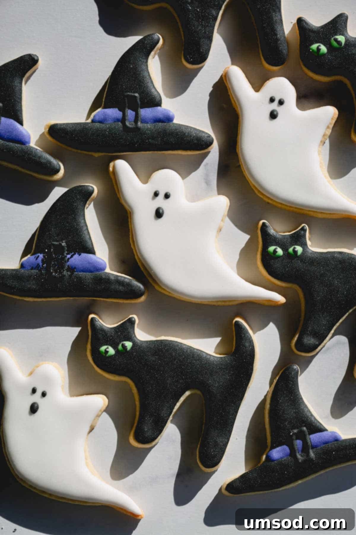 Decorated Halloween sugar cookies as witch hats, ghosts, and black cats.