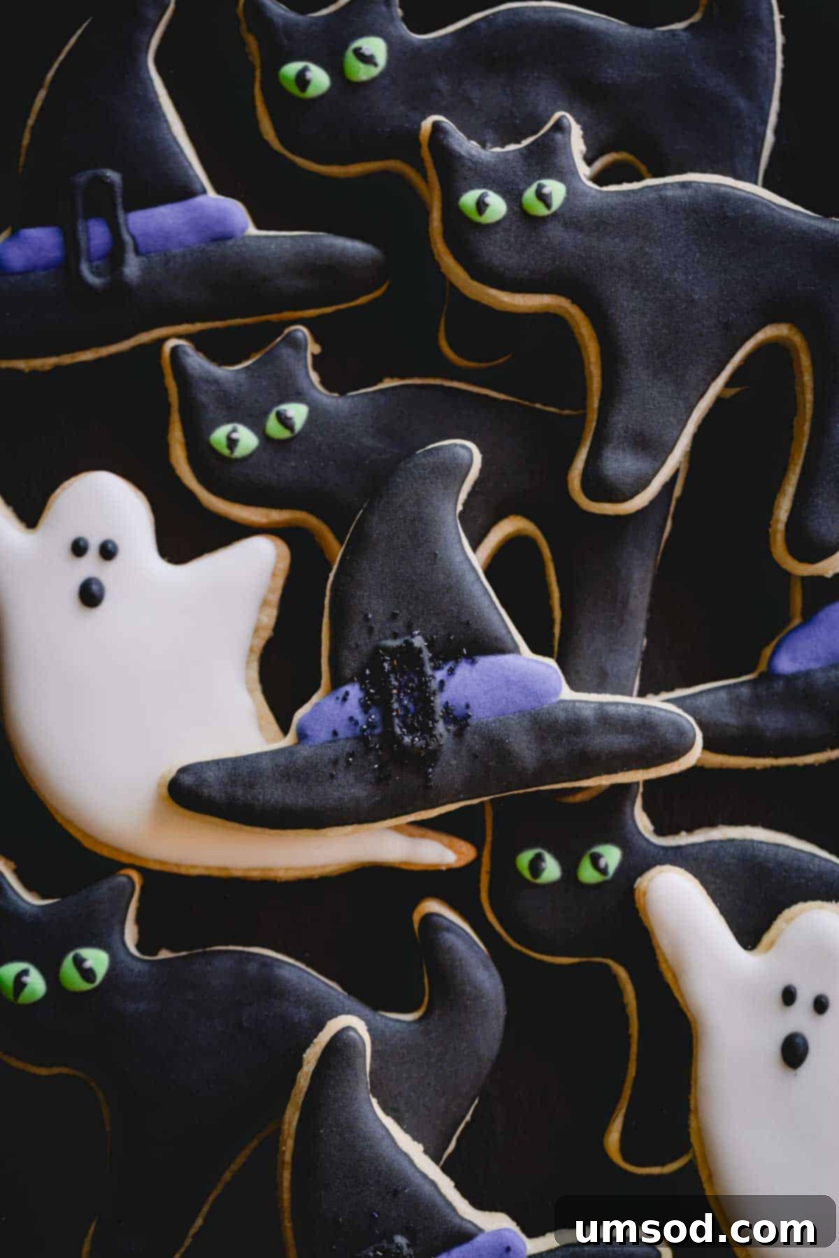 Halloween sugar cookies decorated as ghosts, cats, and witch hats.