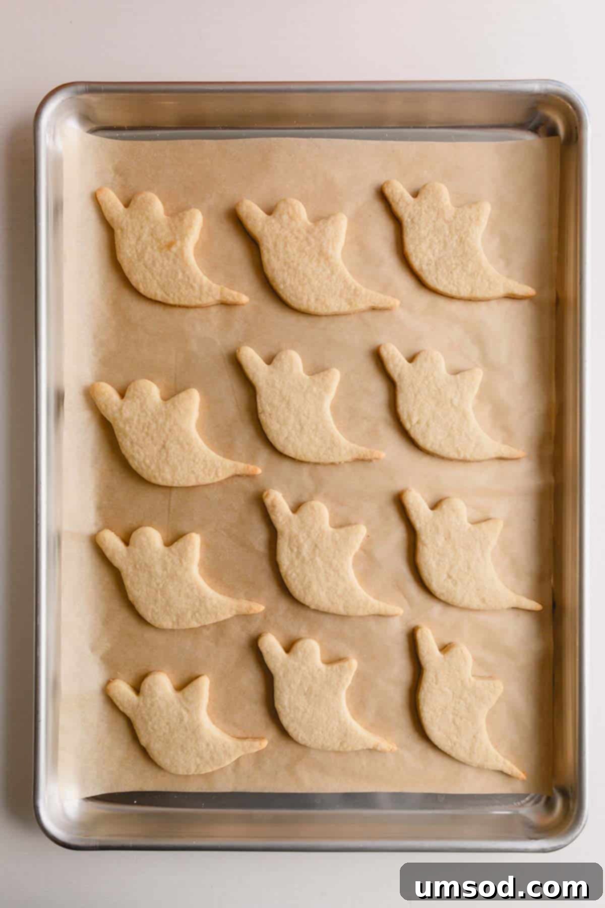 Baked ghost cutout cookies on a baking sheet.