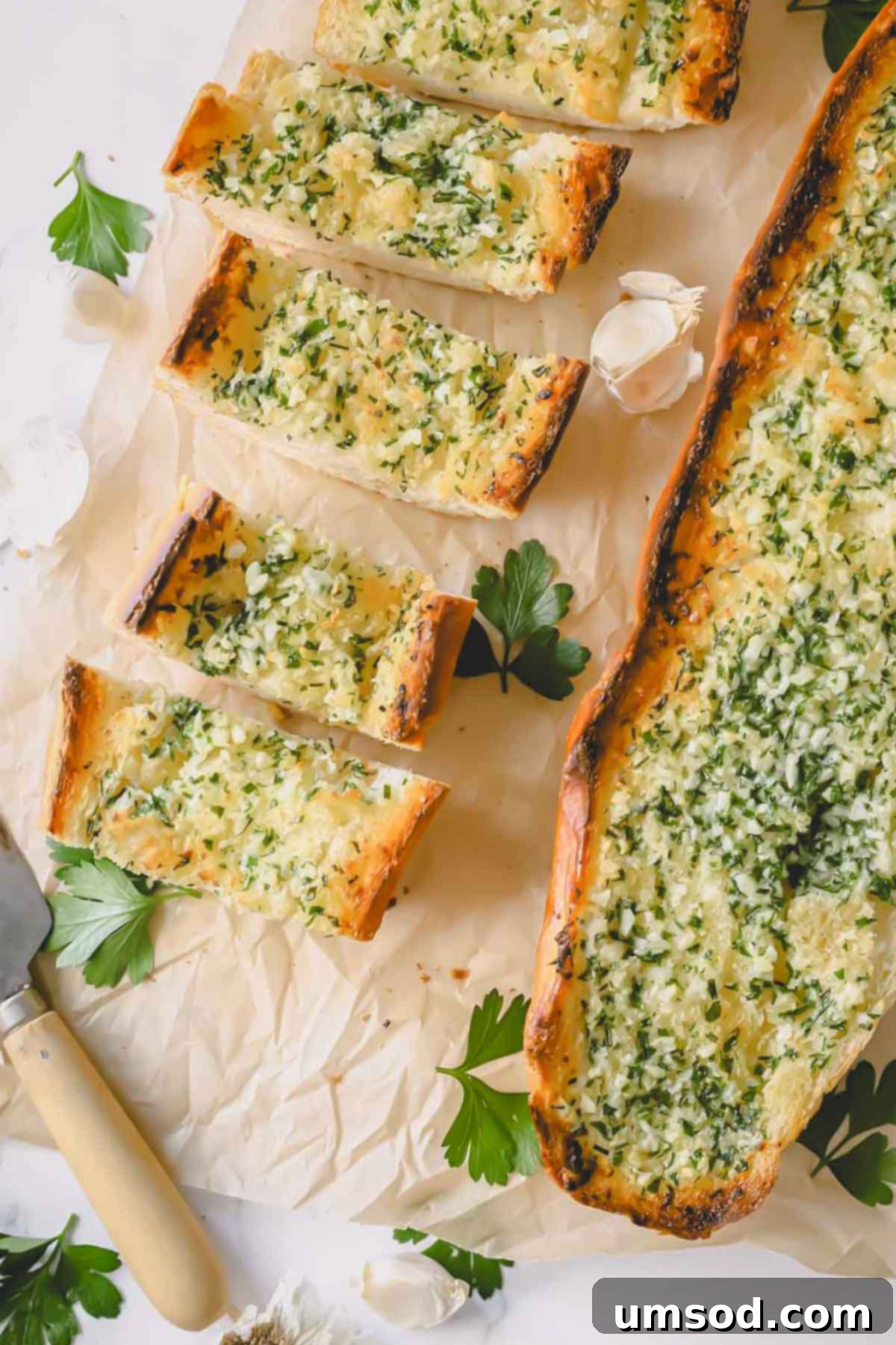 Perfect Garlic Bread in Minutes 7 Pieces of garlic bread next to a whole loaf of baked garlic bread.