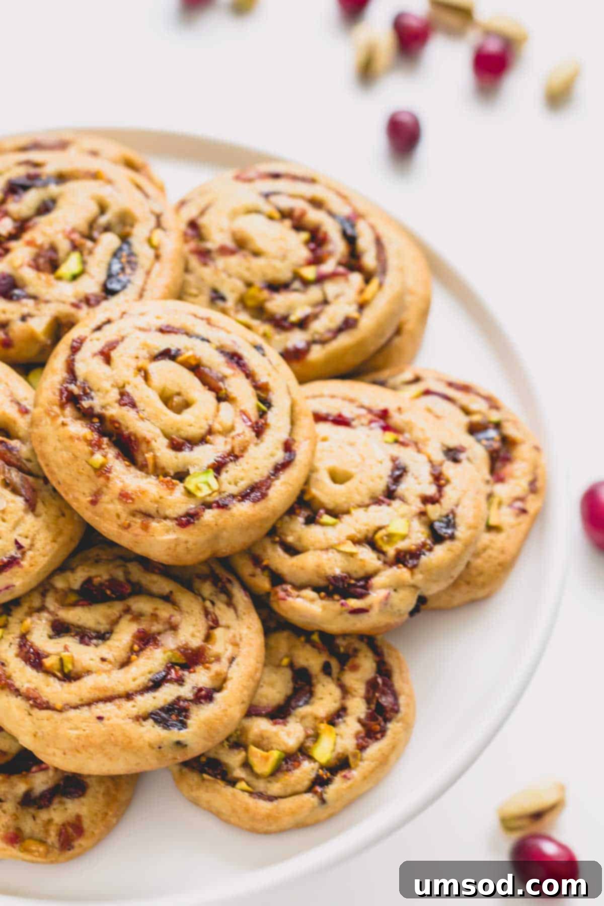 A plate of festive fig, cranberry, and date pinwheel cookies arranged beautifully.
