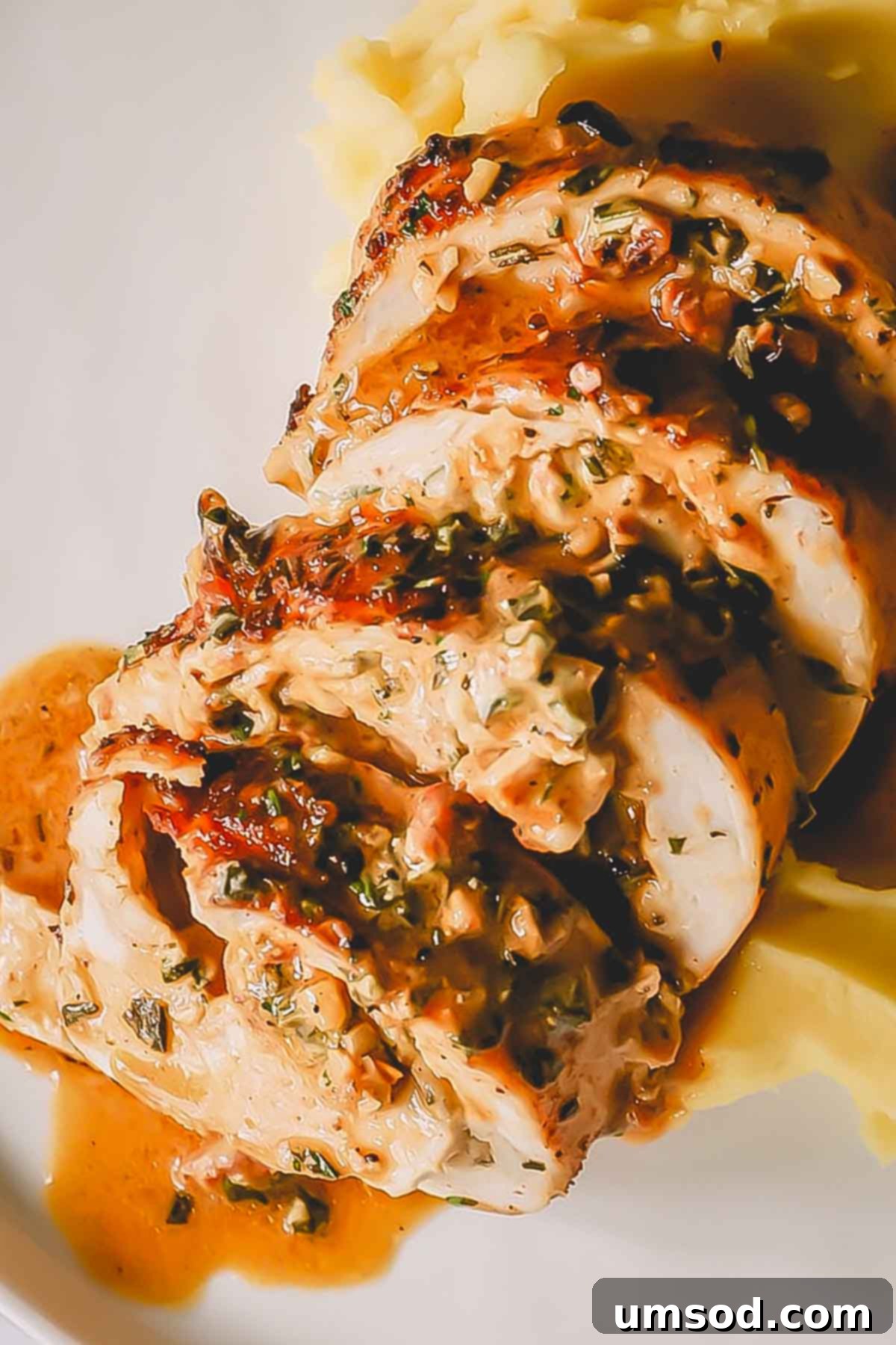 Close-up view of generous slices of roasted stuffed turkey breast, revealing the vibrant and creamy filling with herbs and sun-dried tomatoes.