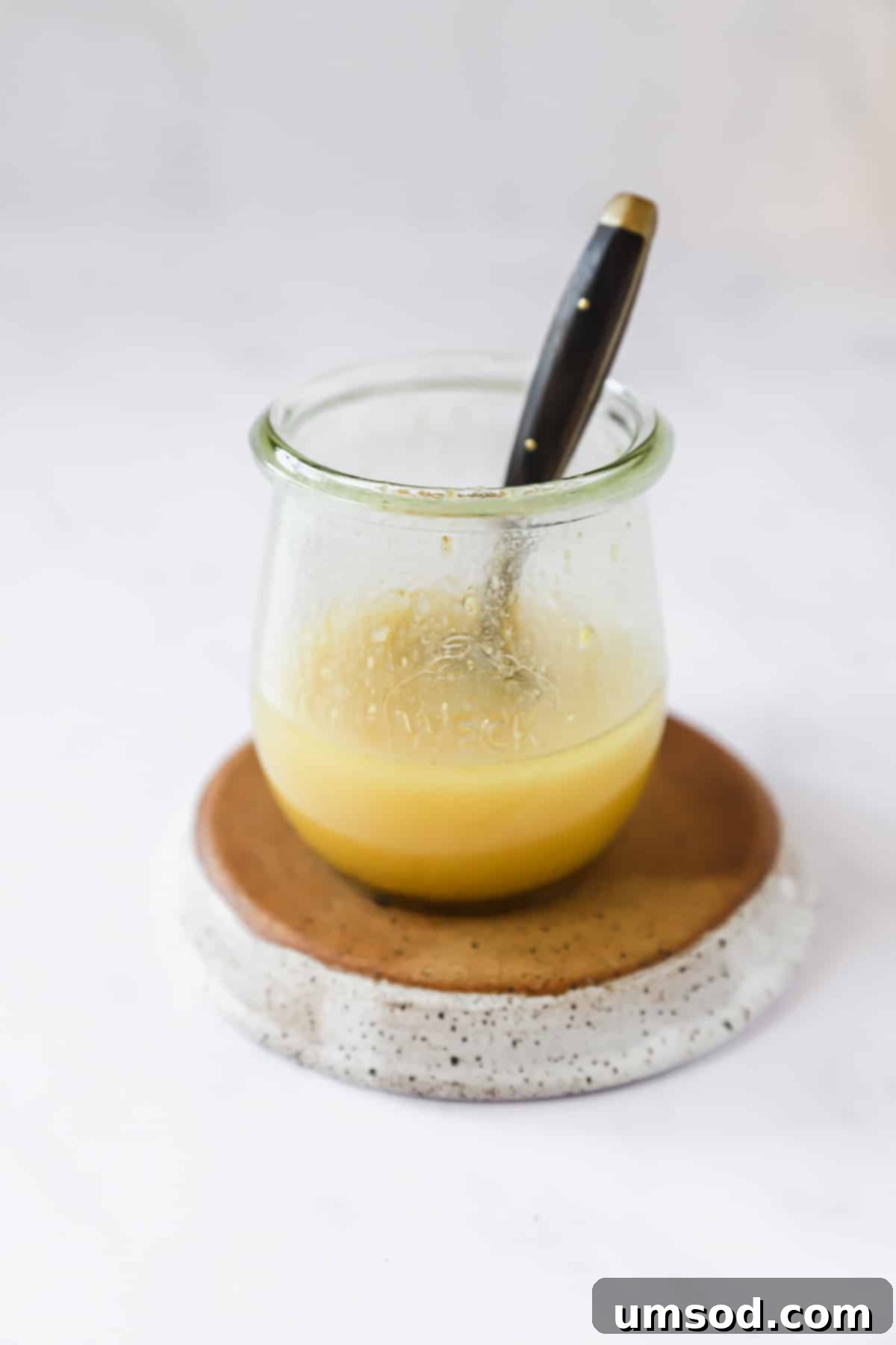 Sunshine Sweet Potato Salad 6 A glass jar filled with homemade honey mustard vinaigrette, with a spoon resting inside, ready for the salad.