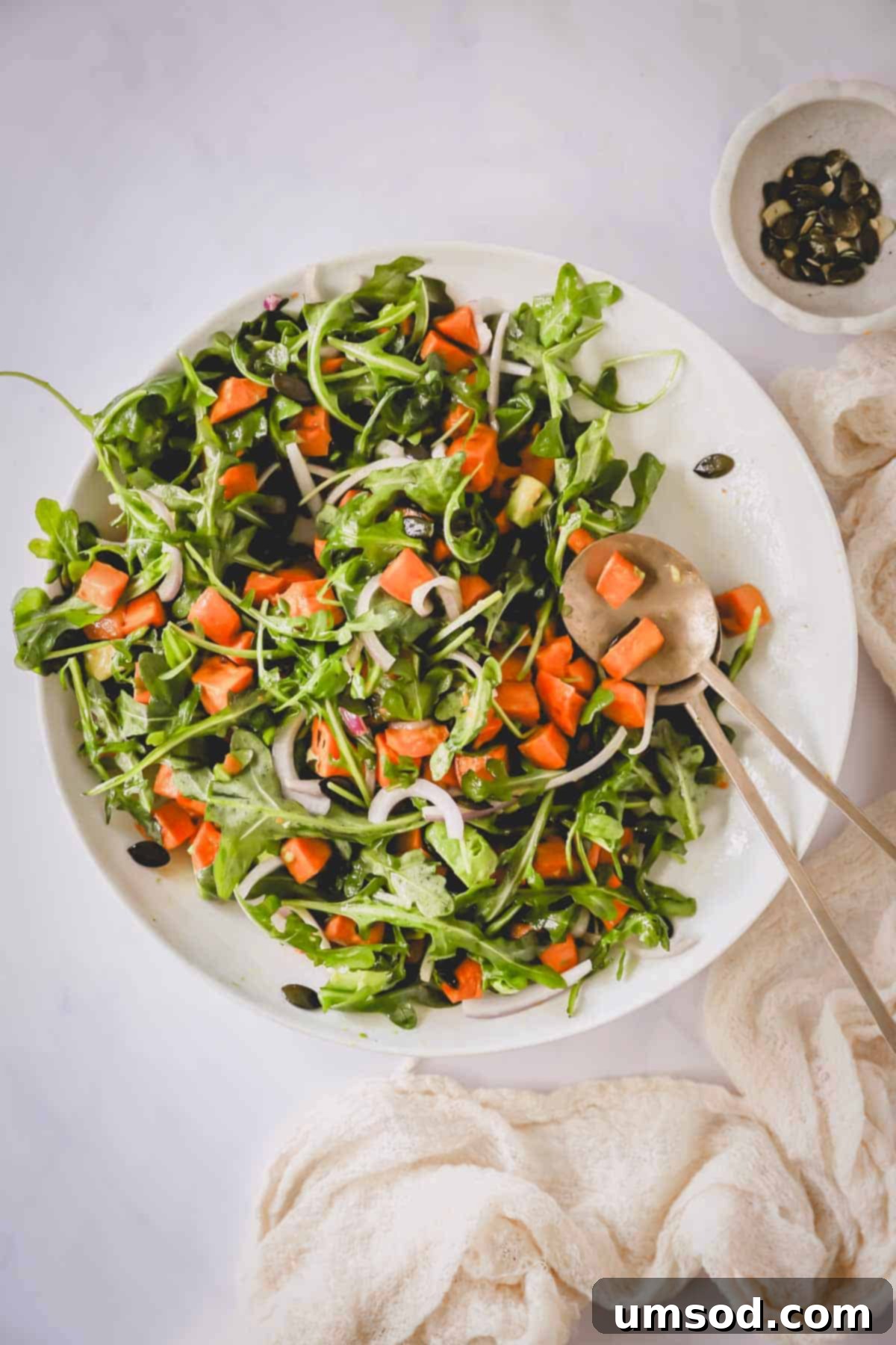 Sunshine Sweet Potato Salad 8 Overhead image of a large bowl of roasted sweet potato salad, garnished and ready to be served, with serving utensils alongside.
