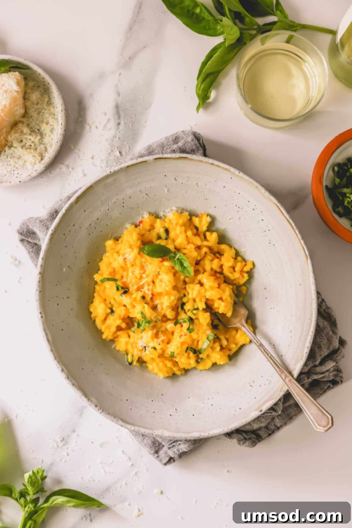 A beautifully presented bowl of saffron risotto with a fork poised to scoop, showcasing its rich golden color and creamy texture.
