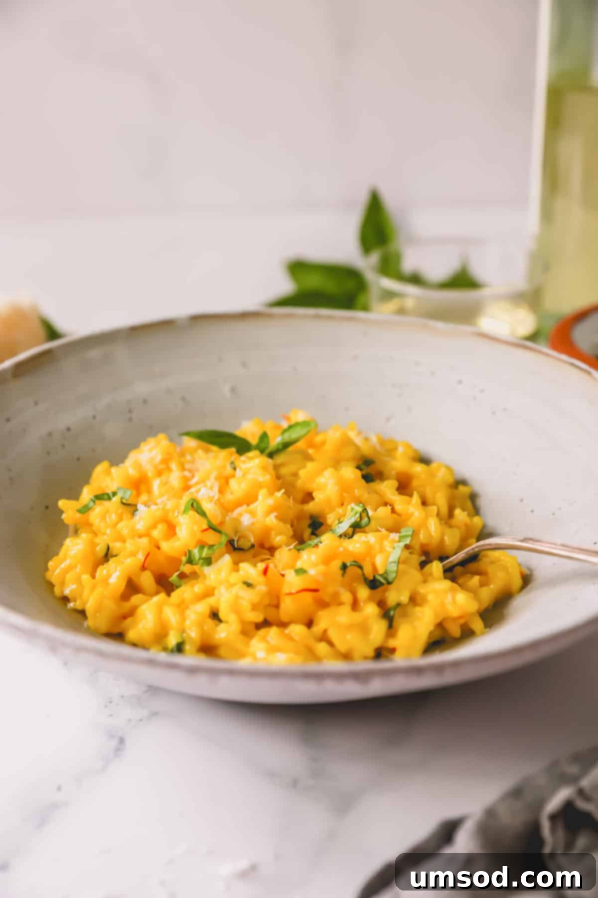 A side view of a bowl of saffron risotto, showing its vibrant color and texture, with a spoon in the dish.