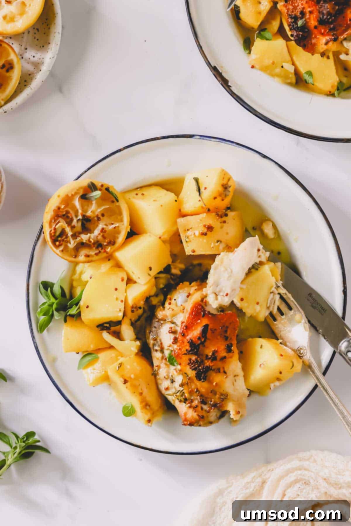 A close-up shot of a plate of Greek lemon chicken and potatoes with a fork holding a bite.