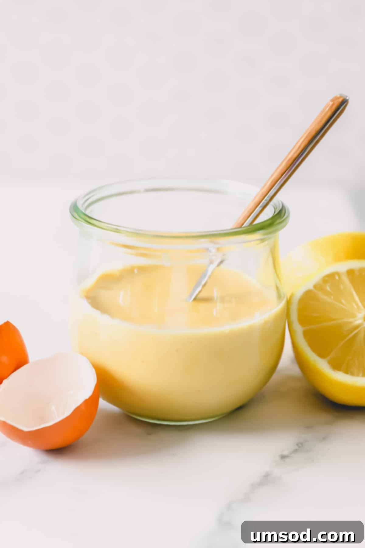 A glass jar filled with freshly made, vibrant yellow hollandaise sauce, ready to be served.