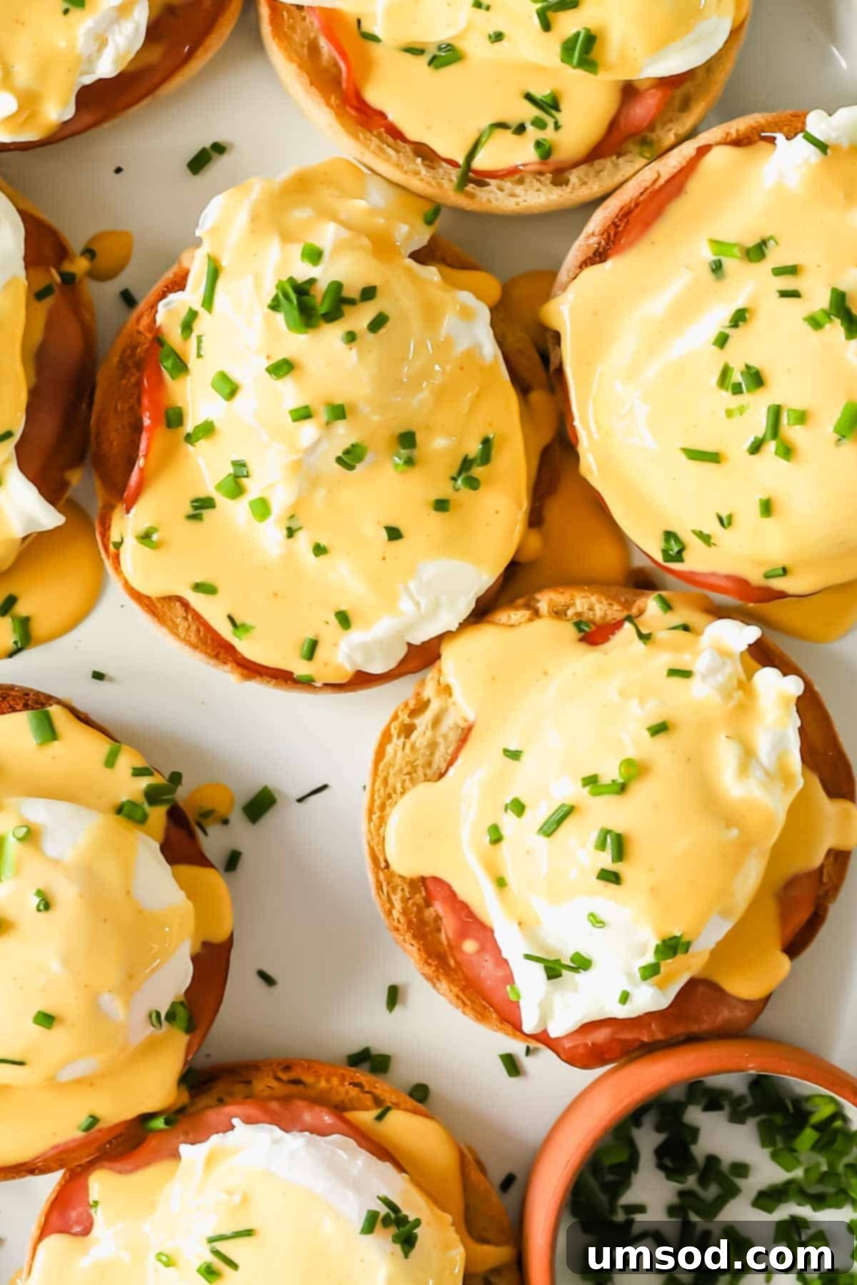 A close-up view of Eggs Benedict garnished with fresh herbs, showcasing the perfectly poached egg and rich hollandaise.