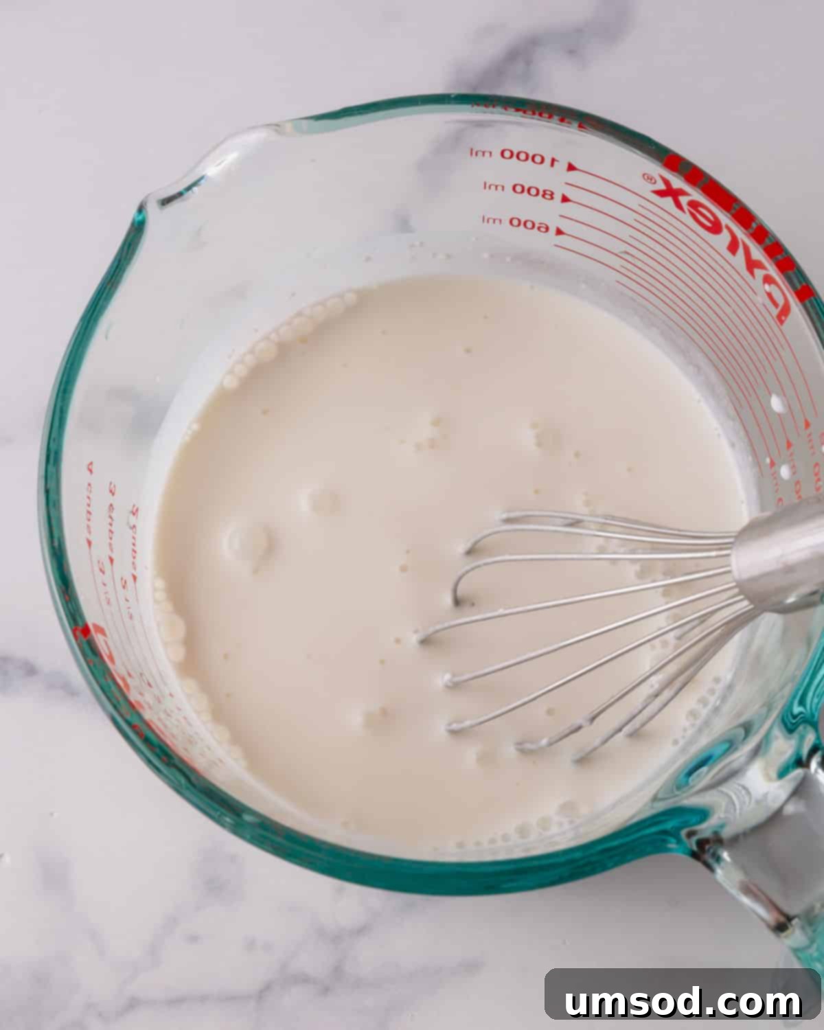 Fluffy White Cake Perfection 6 Wet ingredients for cake being whisked smoothly in a liquid measuring cup, ready for mixing.