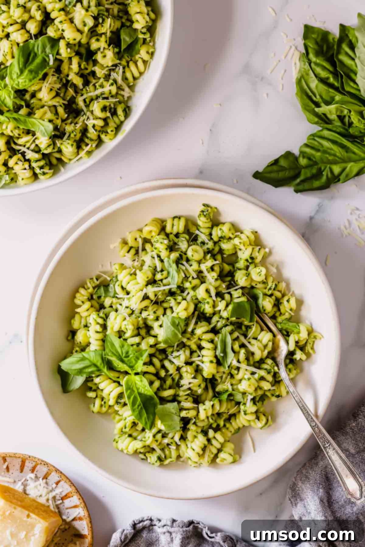 Vibrant Basil Pesto Pasta 8 A bowl of basil pesto pasta with a fork and a second bowl of pasta to the side.