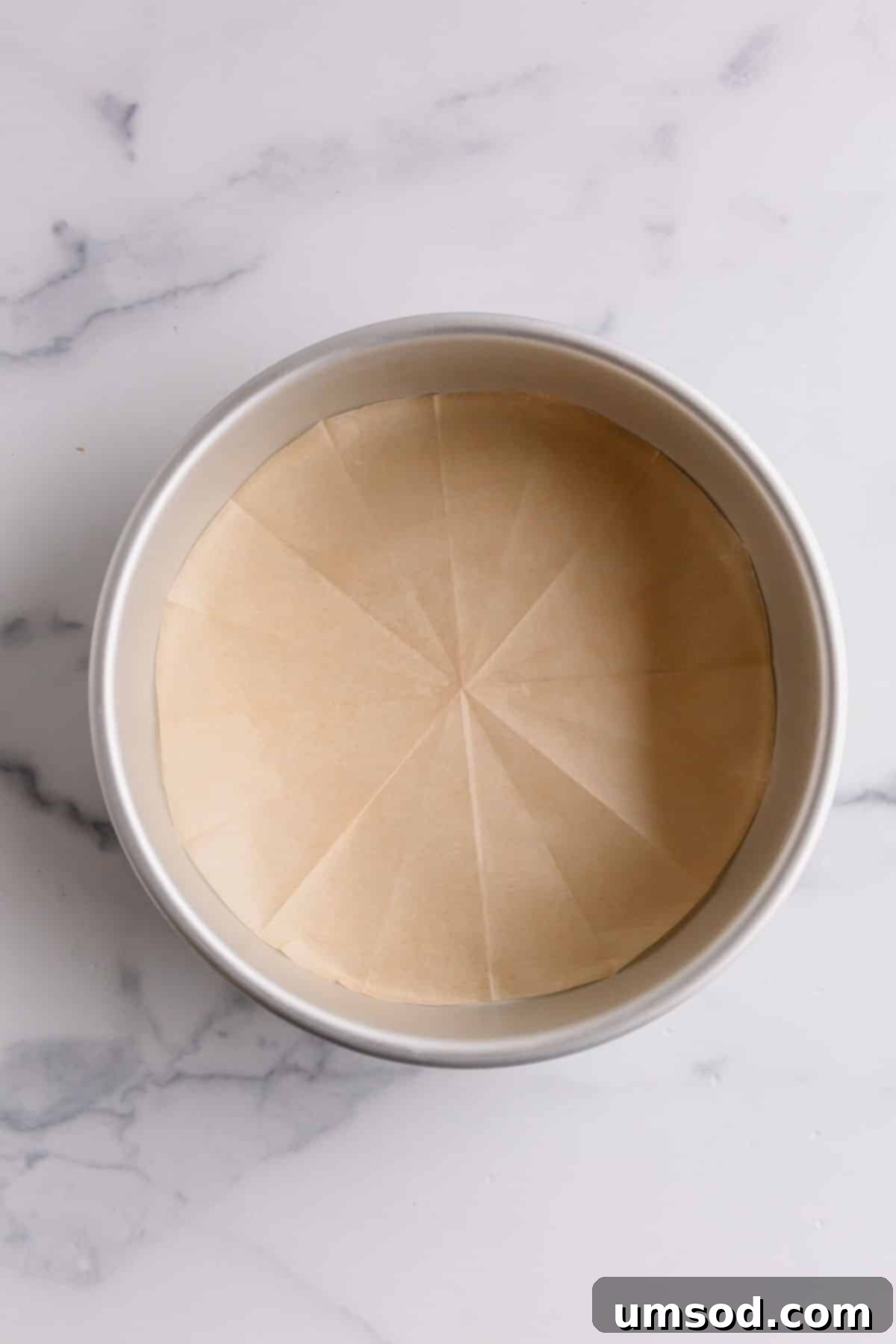 Effortless Parchment Circles for Round Cake Pans 6 A round cake pan showcasing a perfectly cut and placed parchment paper liner, meticulously prepared for baking.