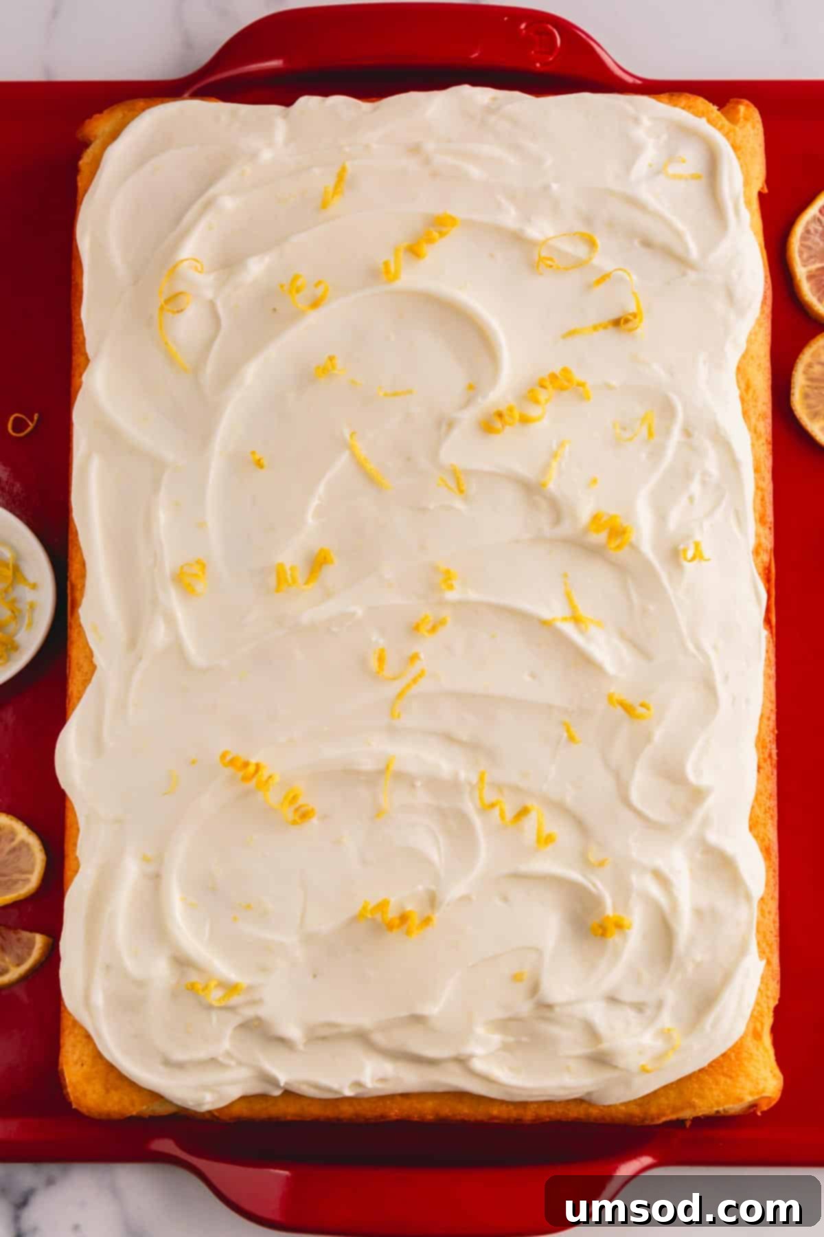 A lemon cream cheese cake topped with lemon cream cheese frosting and lemon zest.