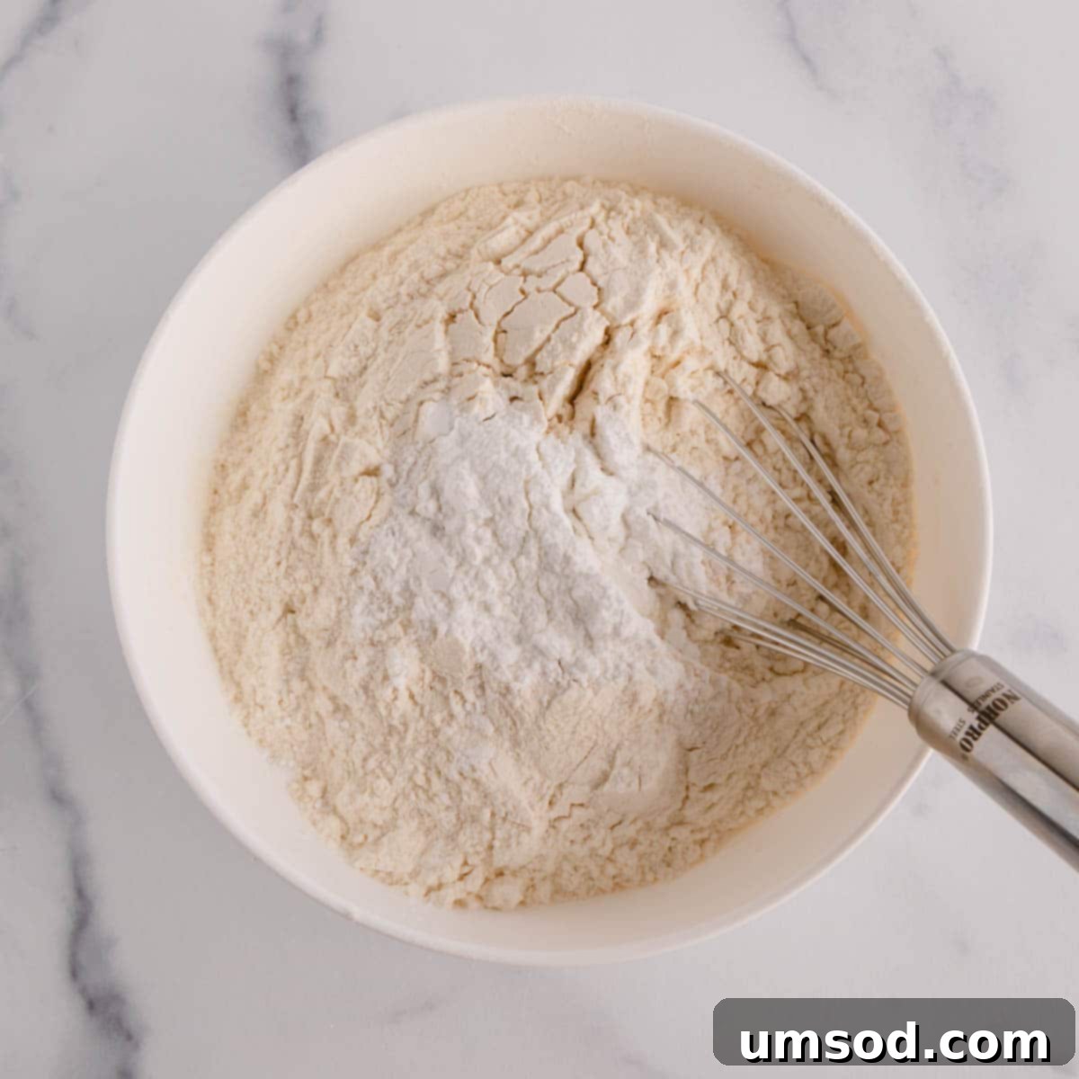 Dry ingredients for lemon sheet cake being whisked in a bowl.