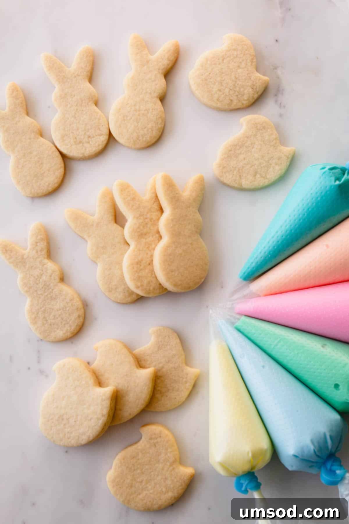 Easter sugar cookies shaped like Peeps and bunnies with pastel royal icing next to them.