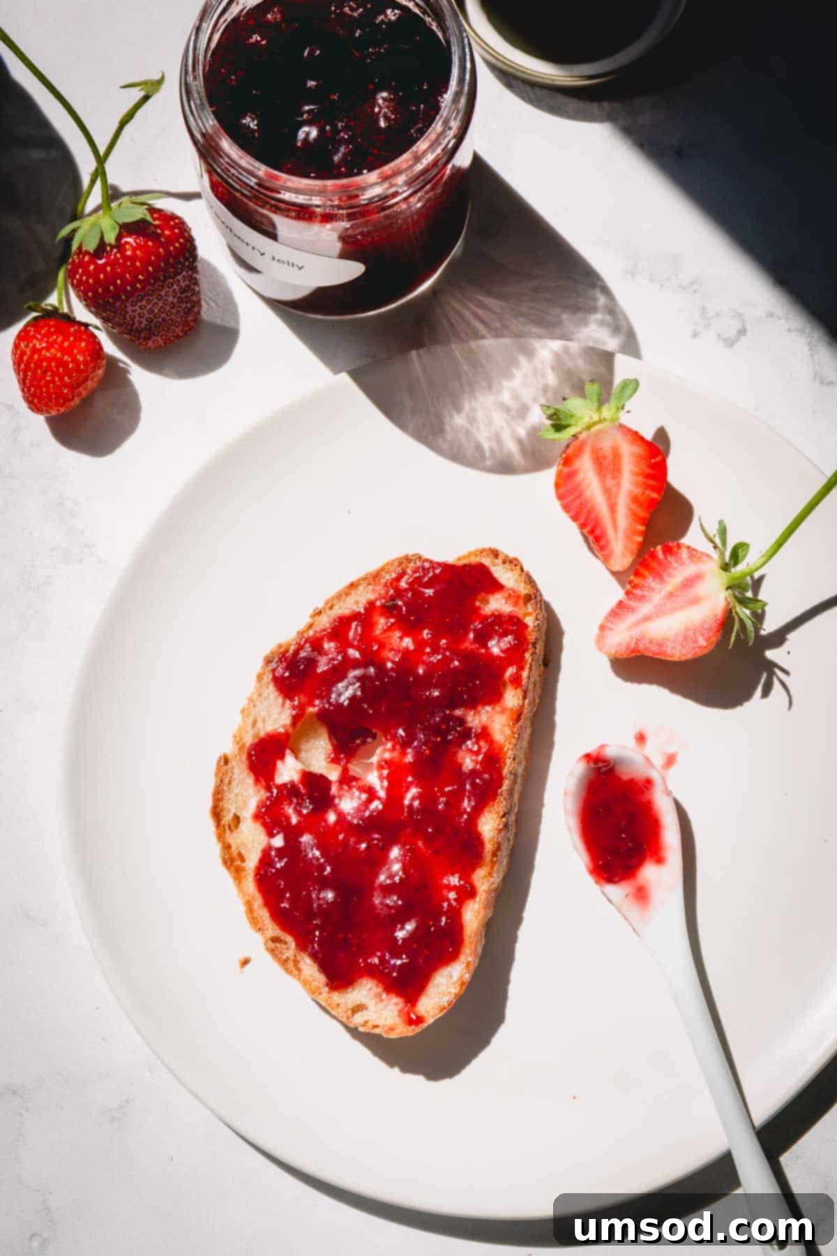 Homemade strawberry jam generously smeared on a slice of rustic bread, highlighting its rich color and spreadable texture.