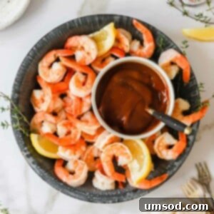 A bowl of cocktail shrimp with cocktail sauce in the center.